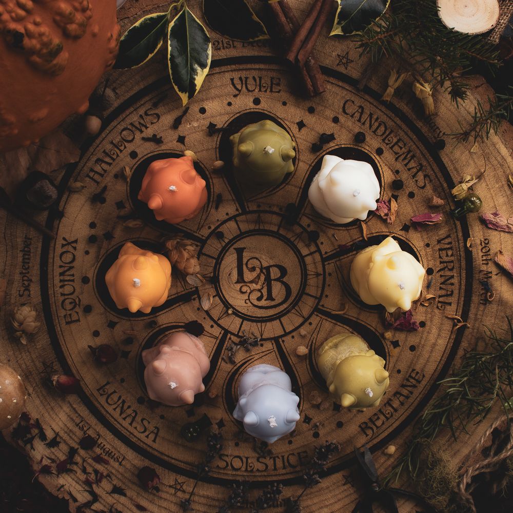 The 8 seasonal Nature Sprites sitting on the Langtree Botanics fragrance wheel of the year. Scattered amongst them are seasonal petals, seeds, fruits and foliage
