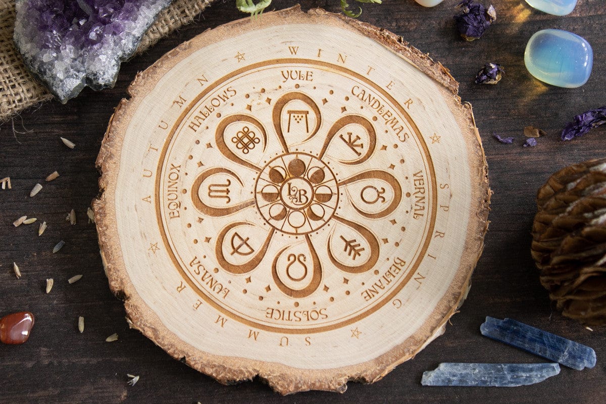Top down view of a decorative wooden placemat displaying the ancient wheel-of-the-year seasonal celebrations amongst crystals