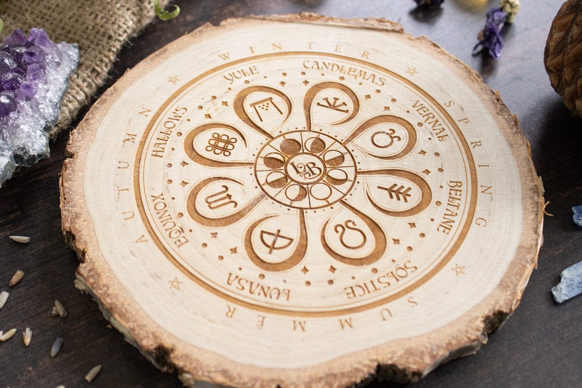 Closeup of a decorative wooden placemat depicting the pagan wheel-of-the-year surrounded by seasonal foliage and crystals