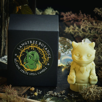 A bright green candle in the shape of a mythical nature sprite sits next to a black cardboard packaging box