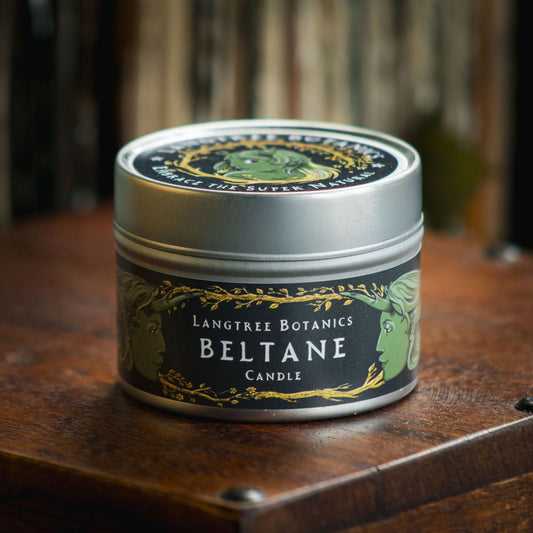 Aluminium tin candle with its lid on sits atop an antique wooden box displaying the Langtree Botanics fragrance, Beltane