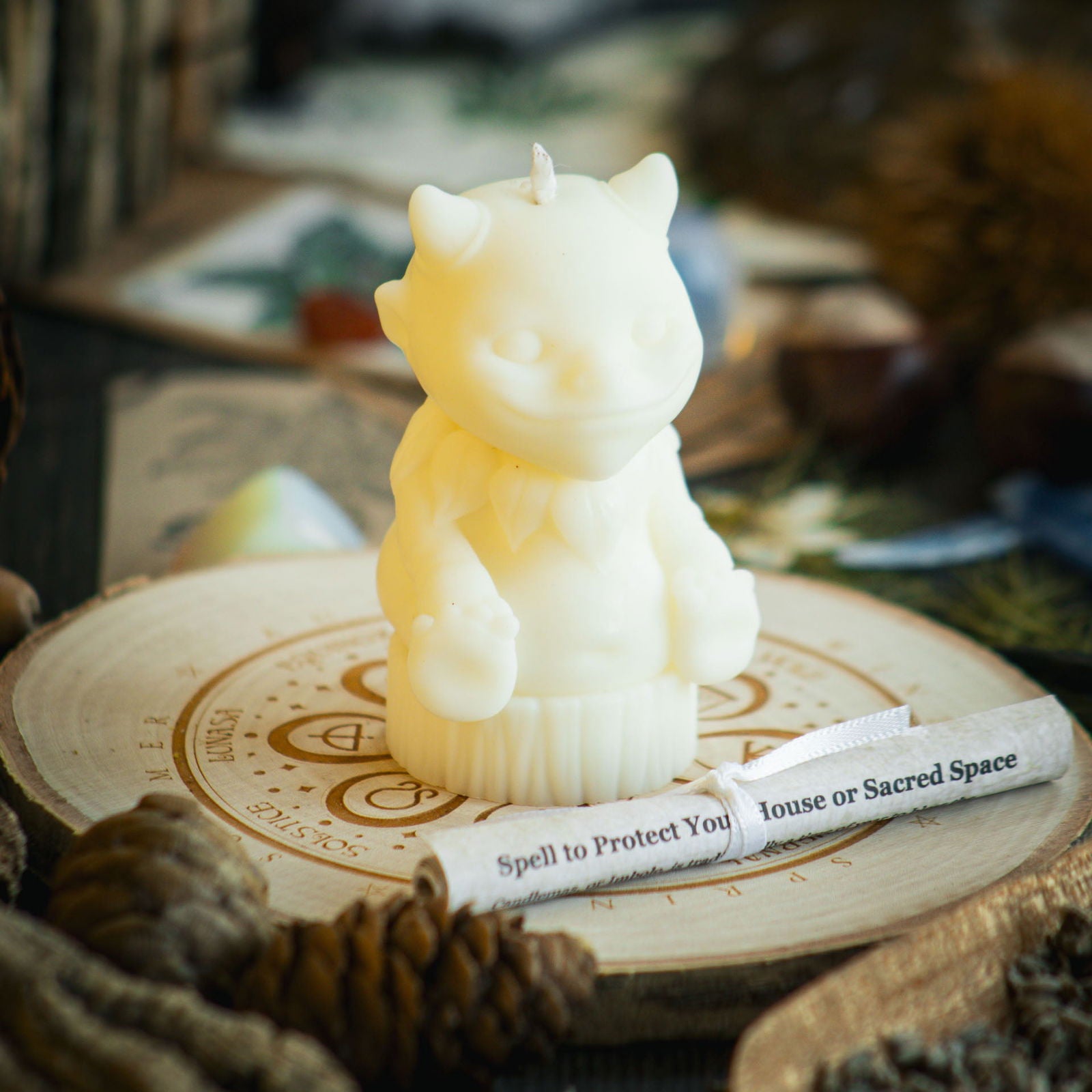 A white candle in the shape of a magical nature sprite sits behind a rolled up spell to celebrate Imbolc