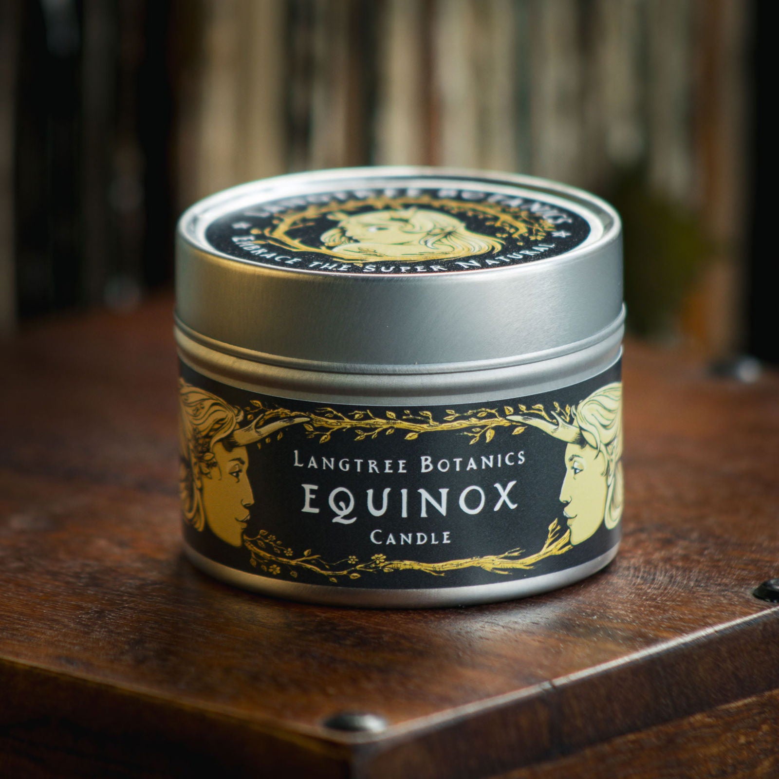 Aluminium tin candle with its lid on sits atop an antique wooden box displaying the Langtree Botanics fragrance, Equinox