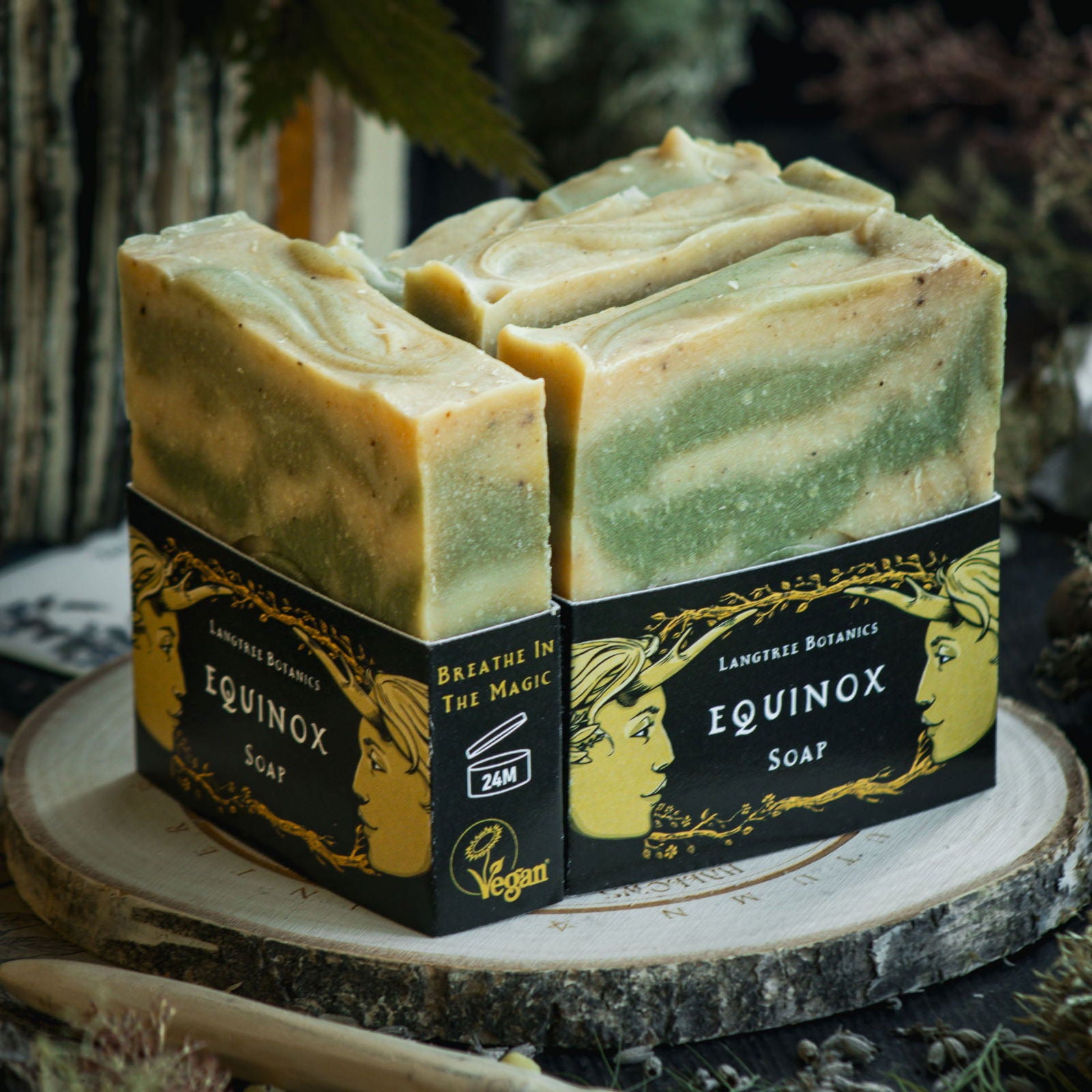 Langtree Botanics autumn collection of four Equinox Soap Bars on a decorative log slice surrounded by seasonal foliage