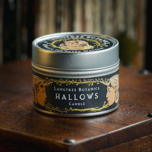 Aluminium tin candle with its lid on sits atop an antique wooden box displaying the Langtree Botanics fragrance, Hallows