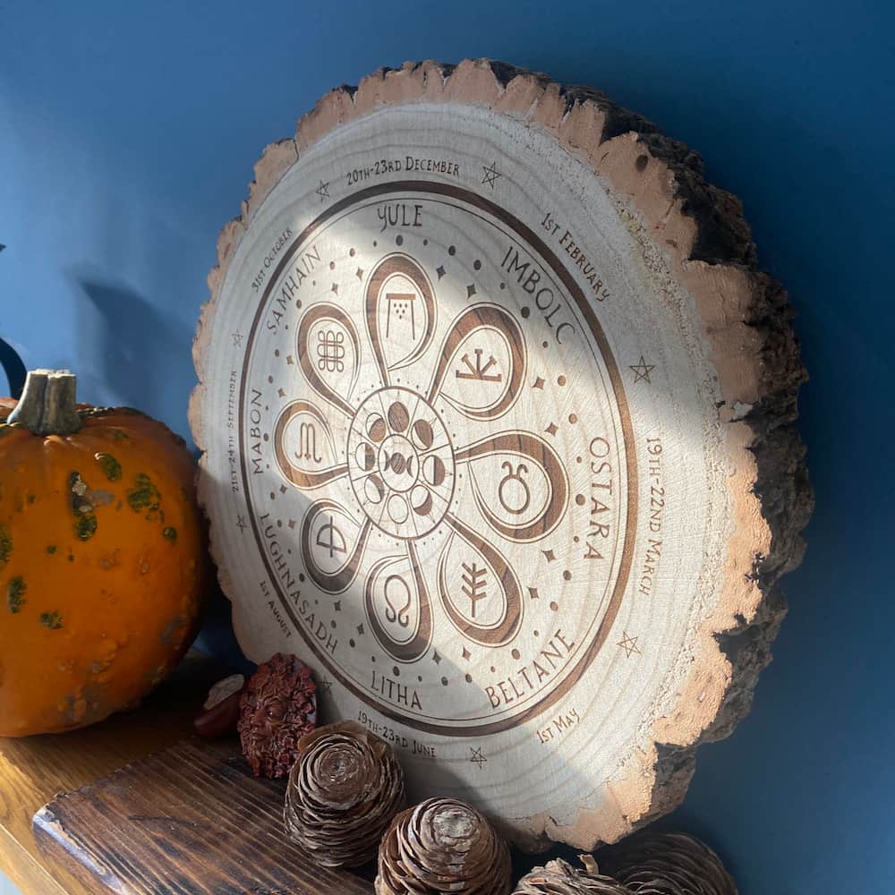 Seasonal Celebration Wheel of the Year Decorative Wooden Slice on a mantlepiece surrounded by cedarwood and a pumpkin