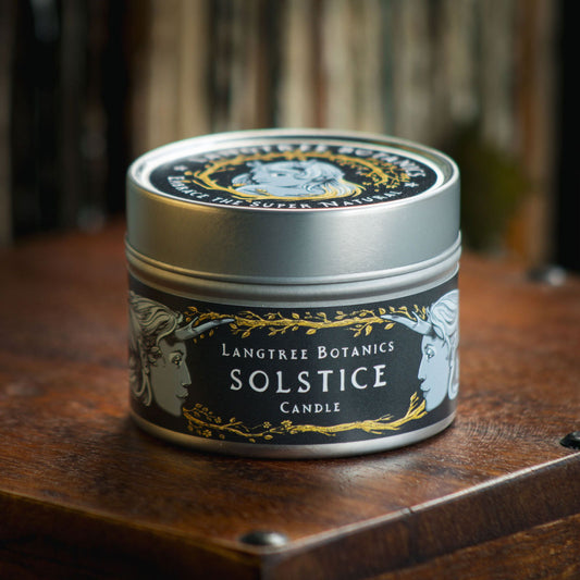 Aluminium tin candle with its lid on sits atop an antique wooden box displaying the Langtree Botanics fragrance, Solstice