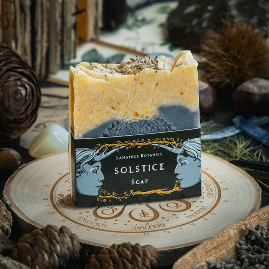 Langtree Botanics summer Solstice Soap Bar on a decorative log slice surrounded by seasonal foliage