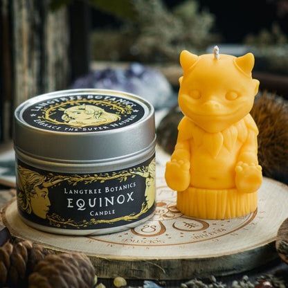 A metal tin container candle sat next to a yellow woodland creature candle on a wooden placemat