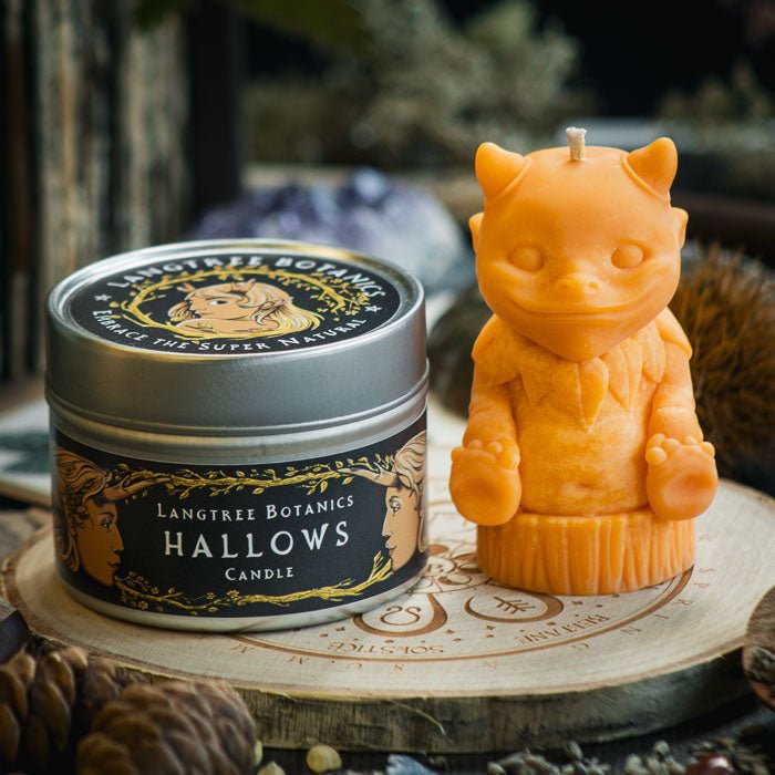 A metal tin container candle sat next to a orange woodland creature candle on a wooden placemat