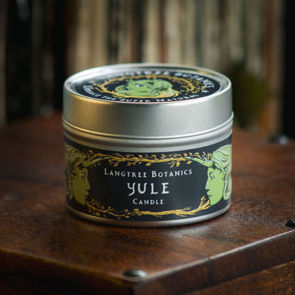 Aluminium tin candle with its lid on sits atop an antique wooden box displaying the Langtree Botanics fragrance, Yule